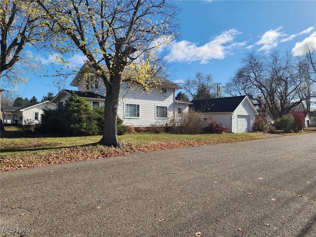 view of front of property featuring a garage, a front lawn, and an outdoor structure