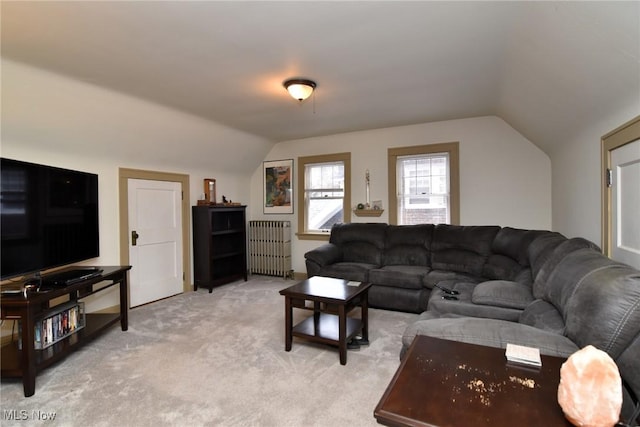 living area featuring lofted ceiling, radiator, and light carpet