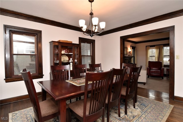 dining area featuring baseboards, ornamental molding, wood finished floors, and an inviting chandelier