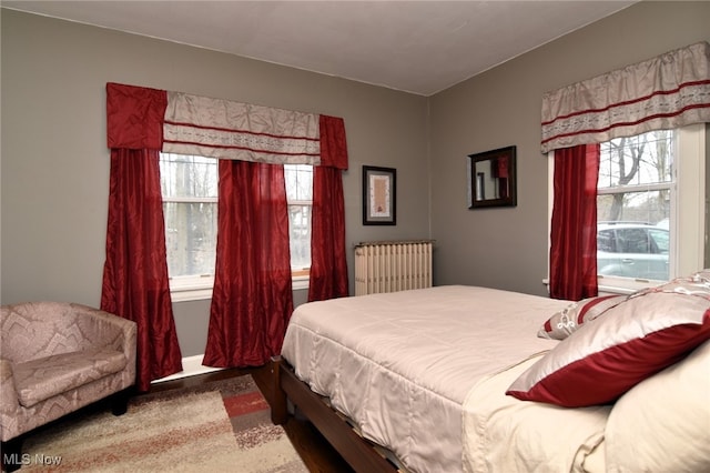 bedroom with baseboards, multiple windows, and radiator heating unit