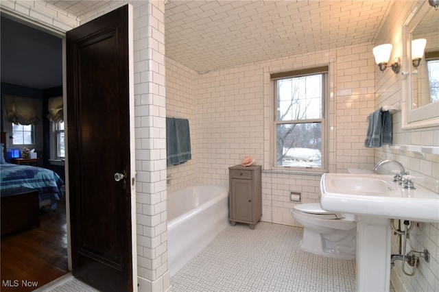 ensuite bathroom with a bath, tile patterned flooring, tile walls, and a healthy amount of sunlight