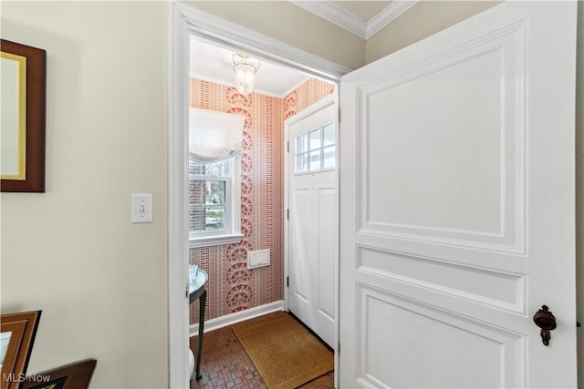 entryway featuring an inviting chandelier, crown molding, baseboards, and wallpapered walls