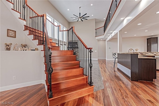 staircase with a ceiling fan, baseboards, and wood finished floors