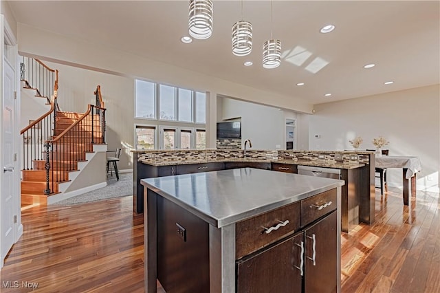 kitchen with dark brown cabinetry, a large island, light wood-style floors, stainless steel counters, and backsplash