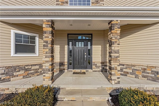 doorway to property featuring stone siding and a porch