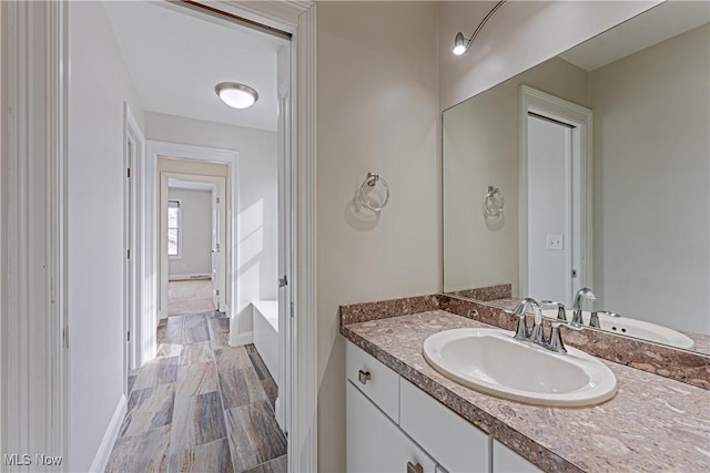 full bath with a bathtub, vanity, and baseboards