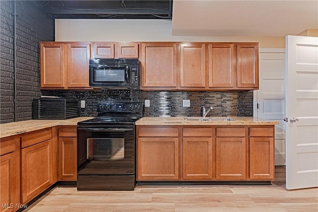 kitchen with light wood-style floors, a sink, backsplash, and black appliances