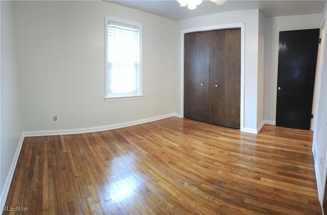 unfurnished bedroom featuring a closet, baseboards, and wood finished floors