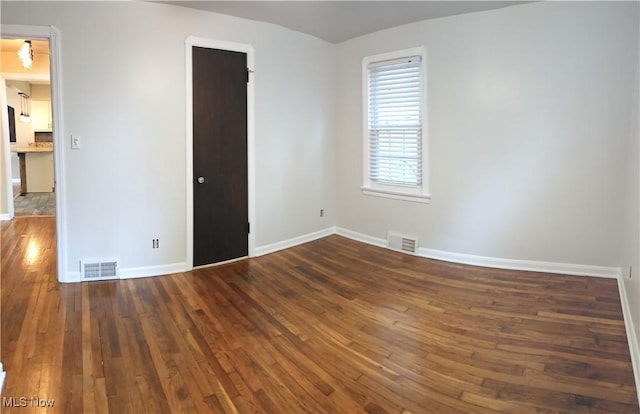 spare room with hardwood / wood-style flooring, visible vents, and baseboards