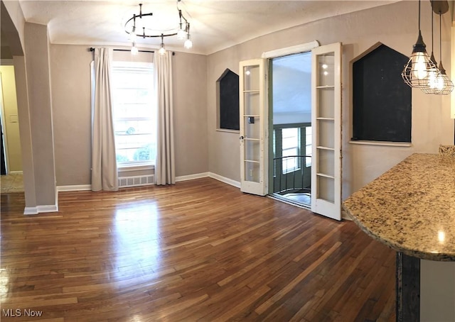 unfurnished dining area with dark wood-style flooring, plenty of natural light, and baseboards