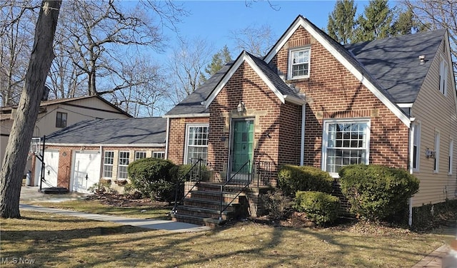 view of front of property with a shingled roof, a front yard, and brick siding