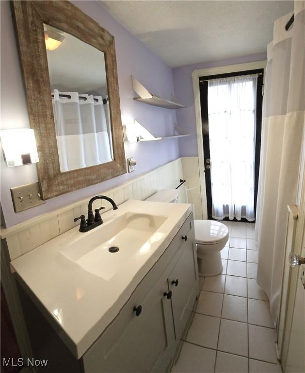 full bath featuring toilet, a shower with curtain, vanity, and tile patterned floors