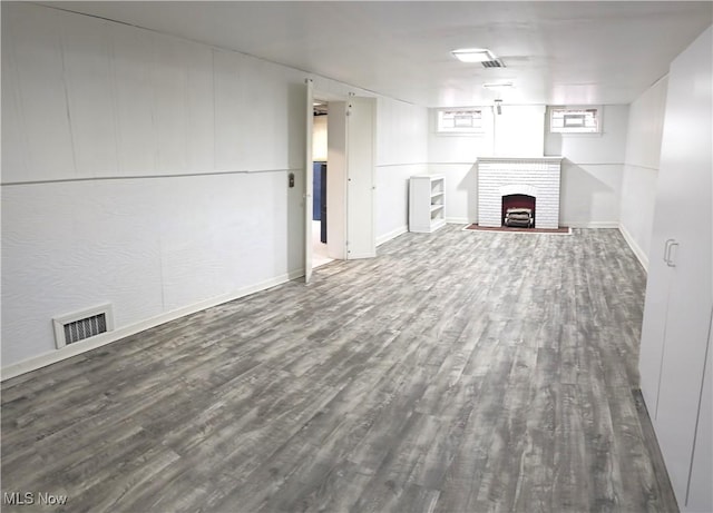 unfurnished living room with a brick fireplace, visible vents, and wood finished floors