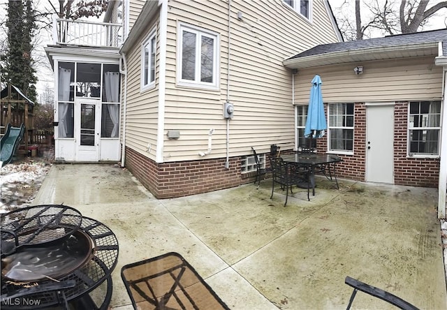 view of patio with outdoor dining space, a sunroom, and a balcony