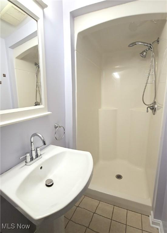 bathroom with a shower stall, a sink, visible vents, and tile patterned floors