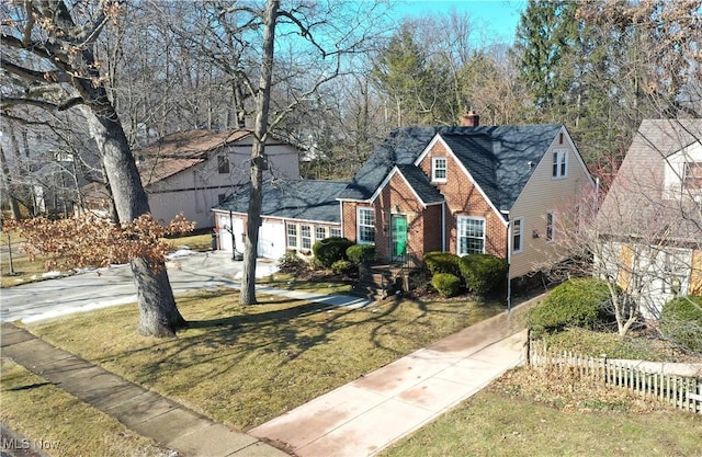 view of front of house featuring driveway, brick siding, an attached garage, fence, and a front yard