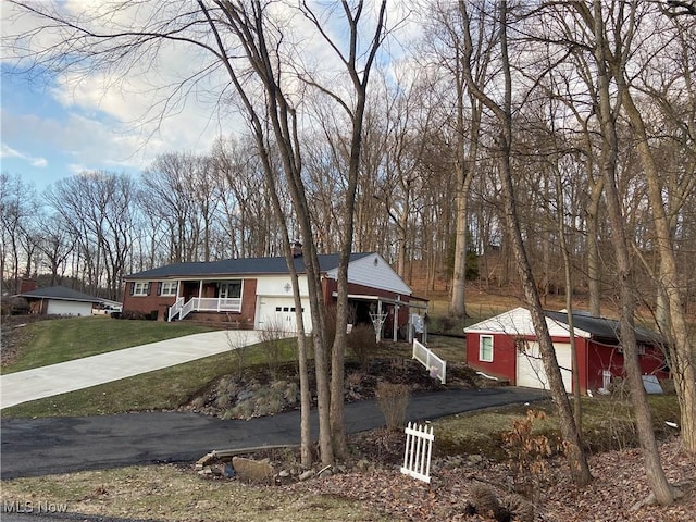 single story home featuring a garage, a front lawn, aphalt driveway, and an outbuilding