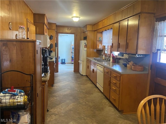 kitchen featuring white appliances, brown cabinetry, and a sink