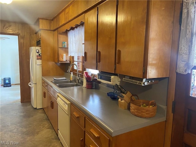 kitchen with white appliances, brown cabinetry, a sink, and light countertops