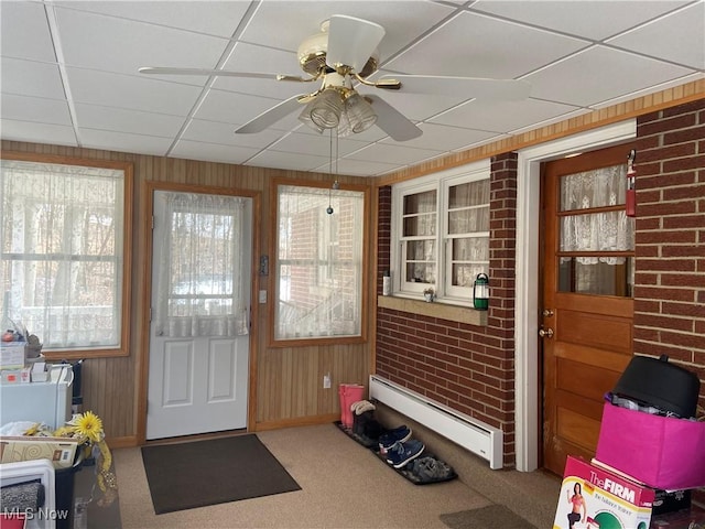 doorway to outside with a paneled ceiling, wood walls, baseboard heating, and carpet flooring