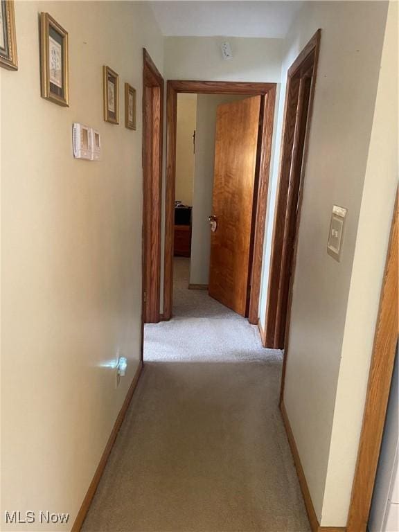 hallway with light colored carpet and baseboards