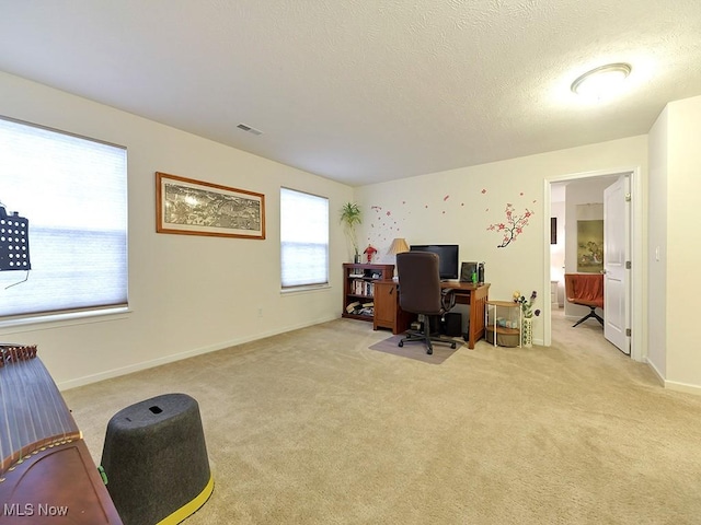 home office with light carpet, baseboards, visible vents, and a textured ceiling