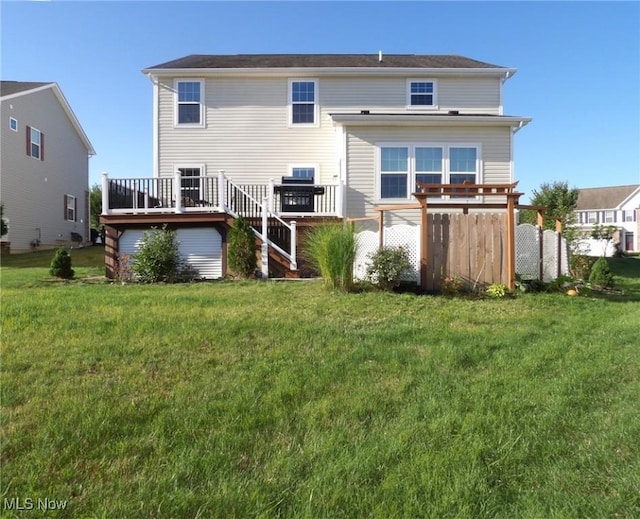 rear view of property featuring a lawn, a wooden deck, and fence