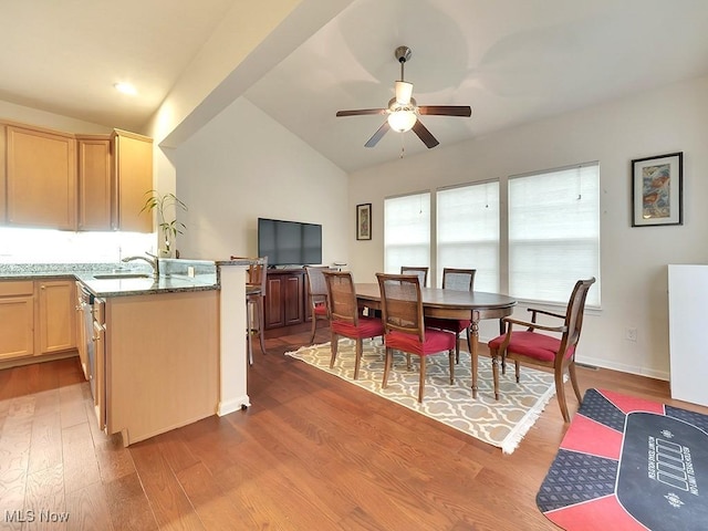 dining space with ceiling fan, vaulted ceiling, baseboards, and wood finished floors