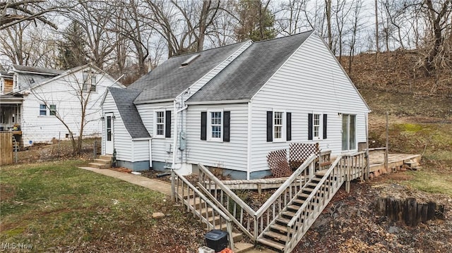 rear view of house featuring entry steps, roof with shingles, a lawn, and a deck