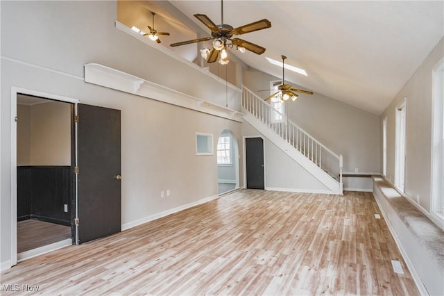 unfurnished living room featuring high vaulted ceiling, stairway, baseboards, and wood finished floors