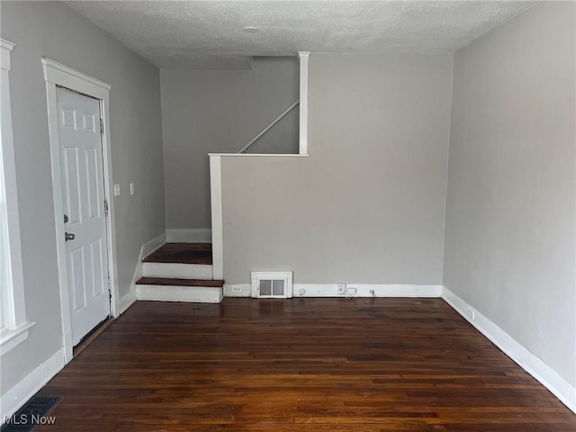 spare room with baseboards, visible vents, wood finished floors, stairs, and a textured ceiling