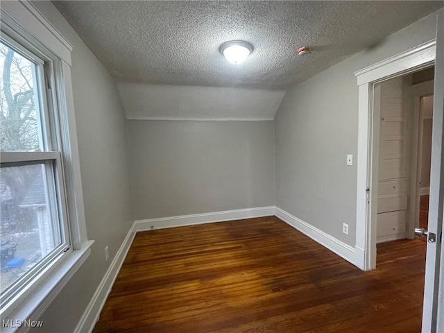 bonus room featuring a textured ceiling, baseboards, vaulted ceiling, and wood finished floors