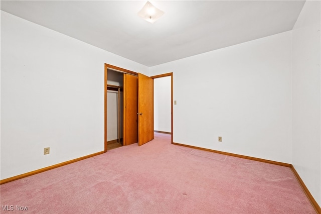 unfurnished bedroom featuring a closet, light colored carpet, and baseboards