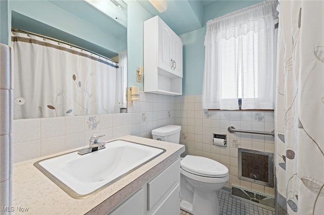 full bathroom featuring toilet, tile walls, vanity, visible vents, and heating unit