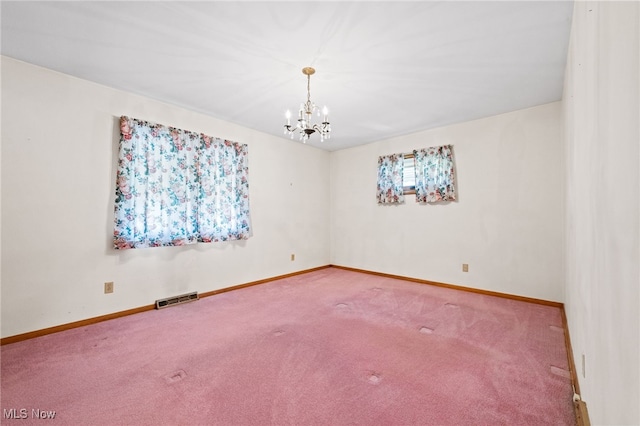 empty room featuring carpet floors, visible vents, a notable chandelier, and baseboards