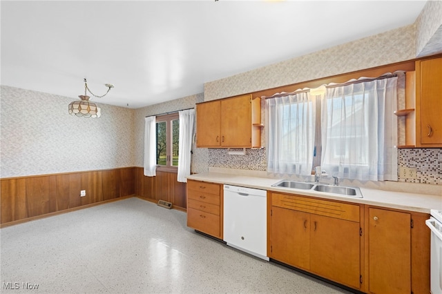 kitchen with white appliances, wallpapered walls, a wainscoted wall, light countertops, and a sink