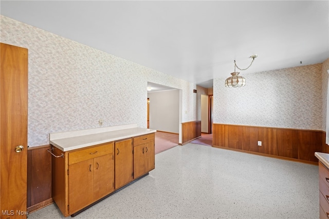 kitchen with wallpapered walls, light countertops, and wainscoting