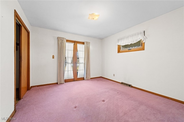 carpeted spare room with visible vents, baseboards, and french doors