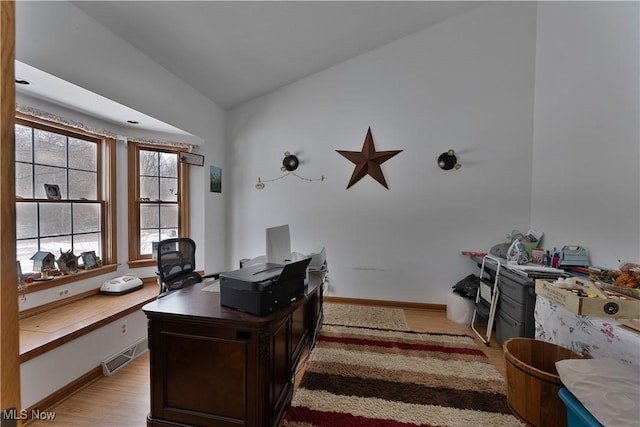 office space with light wood-type flooring, visible vents, vaulted ceiling, and baseboards