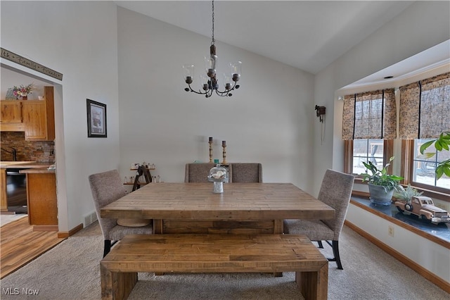 dining area featuring vaulted ceiling, an inviting chandelier, baseboards, and light colored carpet