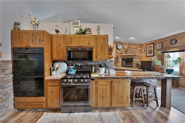 kitchen with dobule oven black, tasteful backsplash, light wood-style flooring, a peninsula, and stainless steel range with gas stovetop