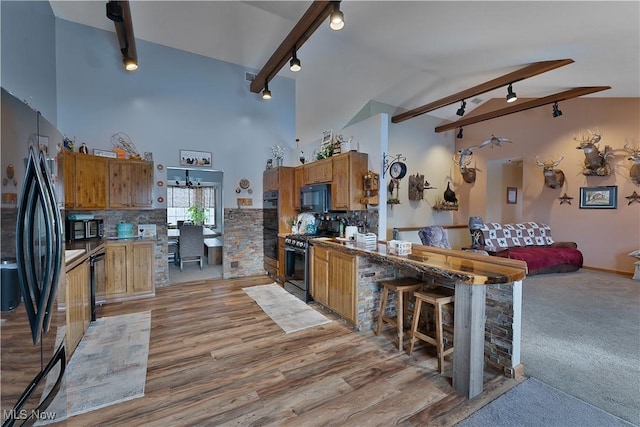 kitchen with brown cabinets, decorative backsplash, light wood-style floors, track lighting, and black appliances