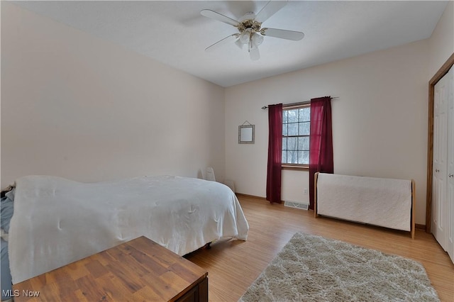 bedroom featuring a ceiling fan, baseboards, visible vents, and wood finished floors