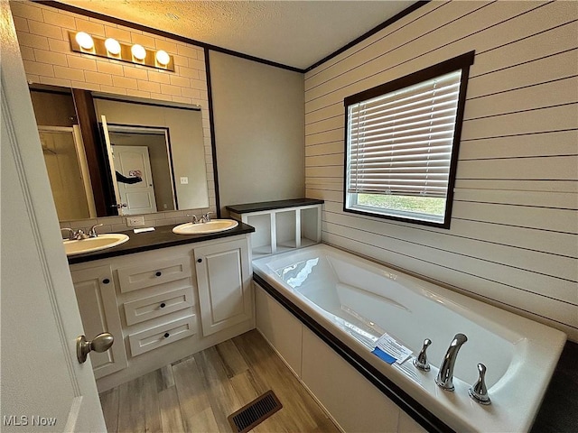 bathroom with visible vents, a sink, a textured ceiling, and wood finished floors