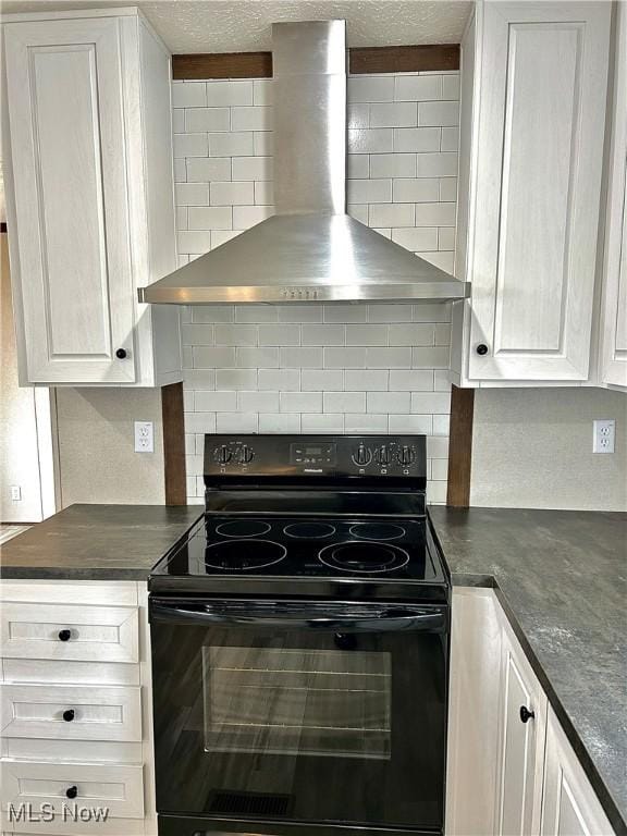 kitchen featuring dark countertops, decorative backsplash, white cabinetry, wall chimney range hood, and black range with electric cooktop