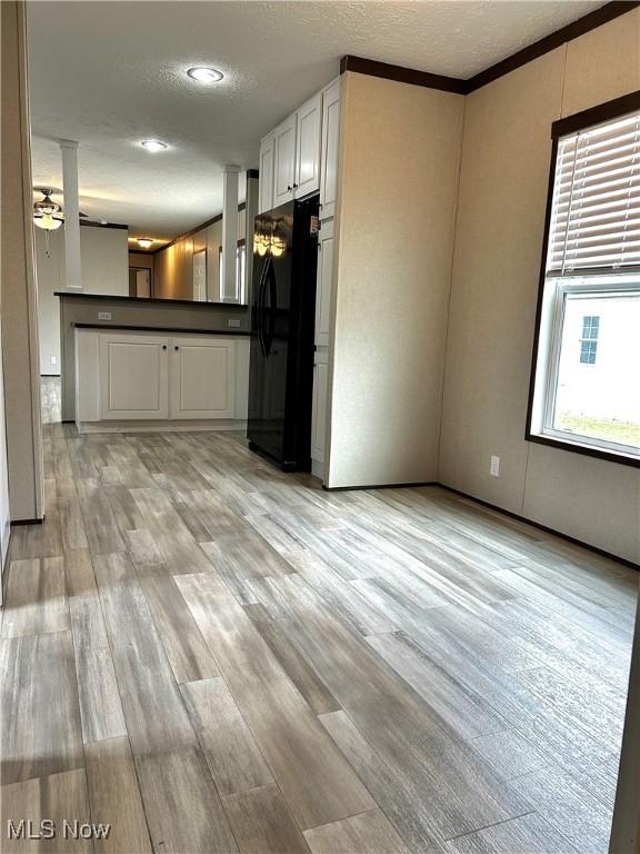 kitchen featuring light wood finished floors, dark countertops, freestanding refrigerator, a peninsula, and a textured ceiling