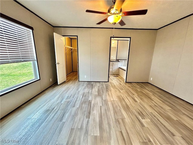 unfurnished bedroom with light wood finished floors, connected bathroom, a ceiling fan, and crown molding