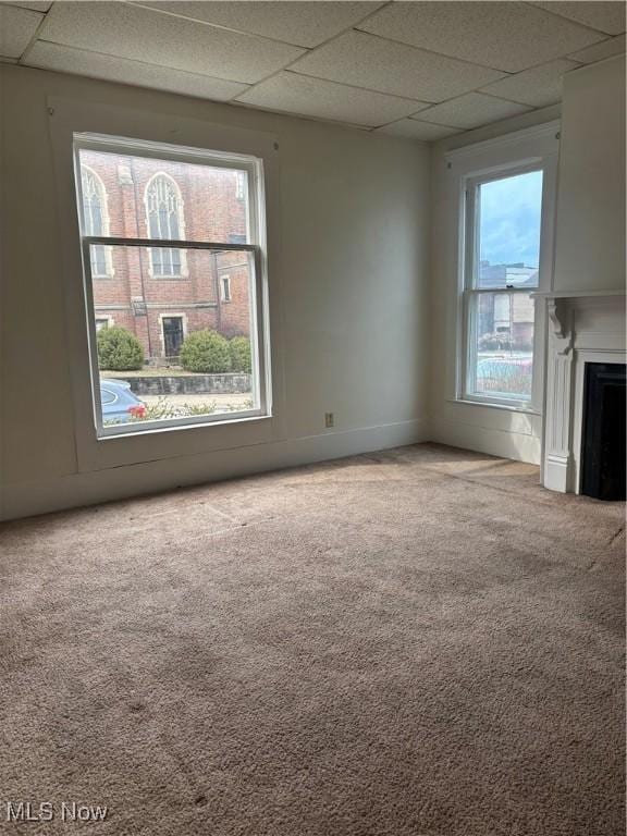 unfurnished living room with carpet floors, a paneled ceiling, and a fireplace