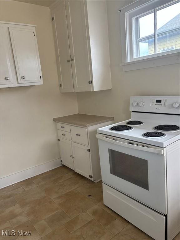 kitchen featuring baseboards, light countertops, white range with electric stovetop, and white cabinetry