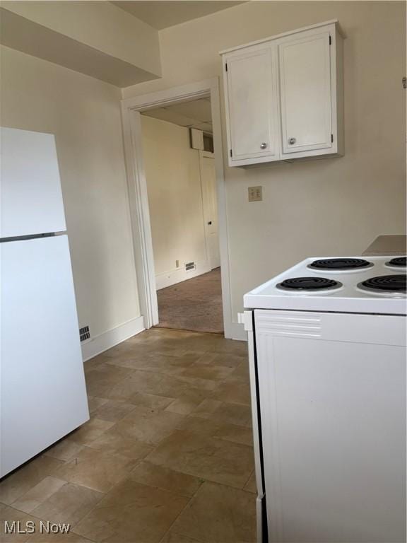 kitchen featuring white appliances, white cabinetry, and baseboards